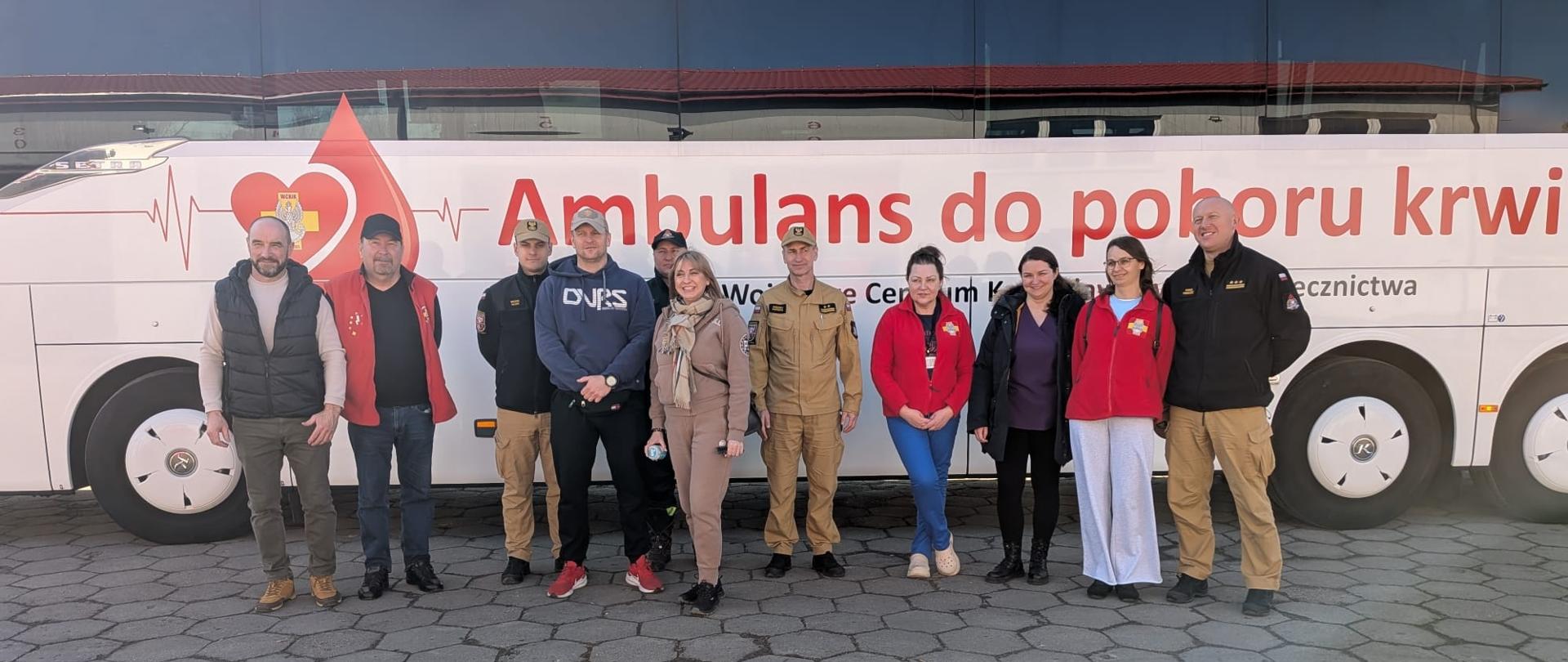 Strażacy stojący na tle krwiobusu