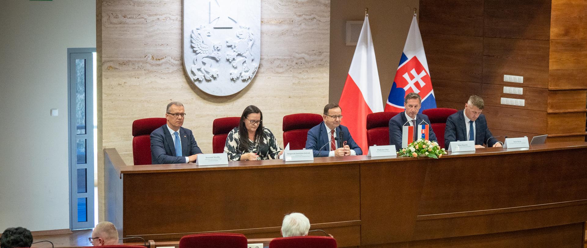Pięć osób siedzi obok siebie przy stole. W samy środku siedzi wiceminister Małgorzata Jarosińska-Jedynak.