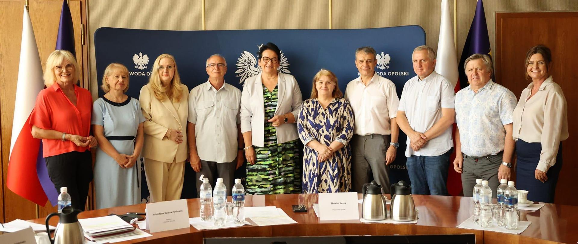 Wojewoda Opolski razem z Dyrektor Wydziału Zdrowia Mirosławą Kwatek-Hoffmann oraz Zastępcą Dyrektora Wydziału Zdrowia Beatą Jabłońską razem z powołanymi konsultantami medycznymi pozują do zdjęcia, stojąc w Sali Złotej przed stołem