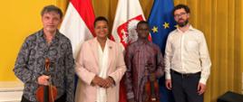 Pamiątkowe zdjęcie z koncertu w Ambasadzie RP w Hadze. Cztery osoby stoją obok siebie, zwrócone w stronę obiektywu. Od lewej: Michał Buczkowski, Ambasador RP Margareta Kassangana, Stephen Otieno oraz Andrew Wright