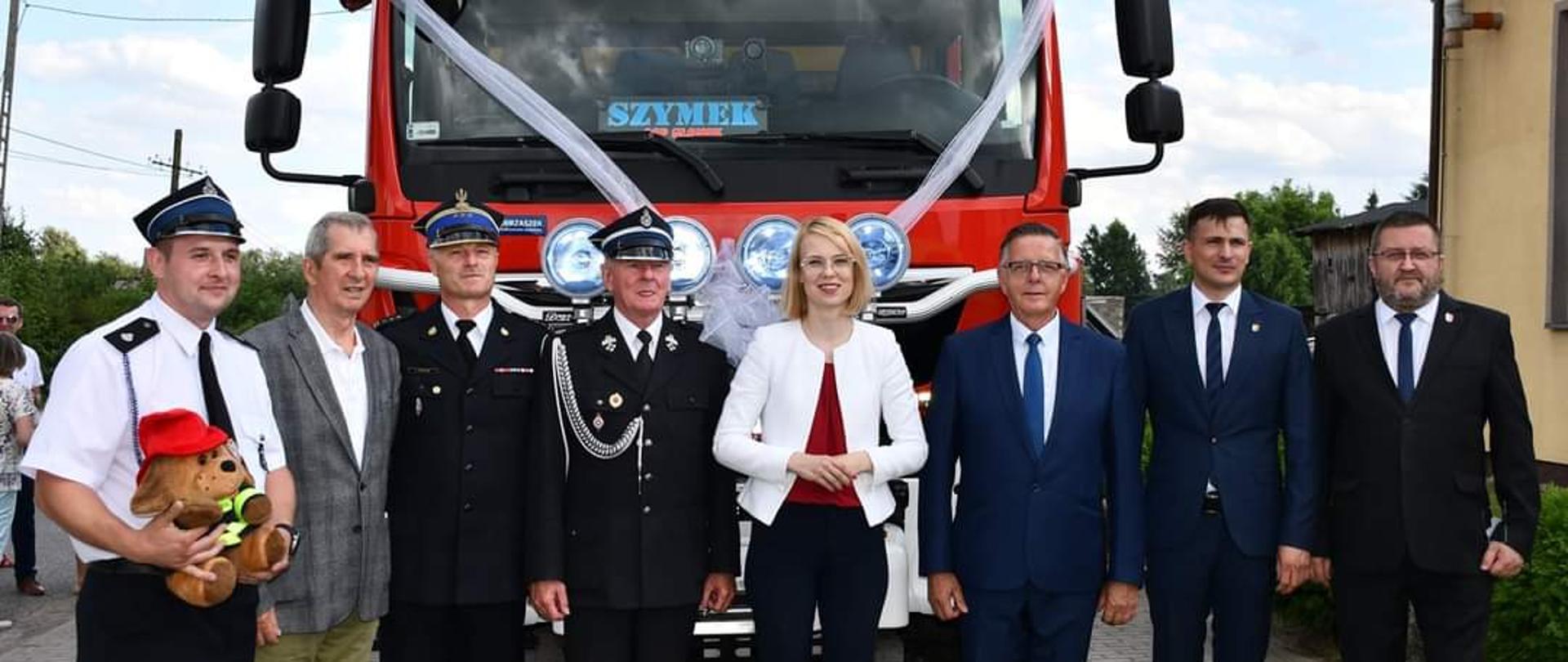 Na zdjęciu w tle poświęcony pojazd pożarniczy Man TGM 13.290 o napędzie 4x4, przed pojazdem zaproszeni goście.