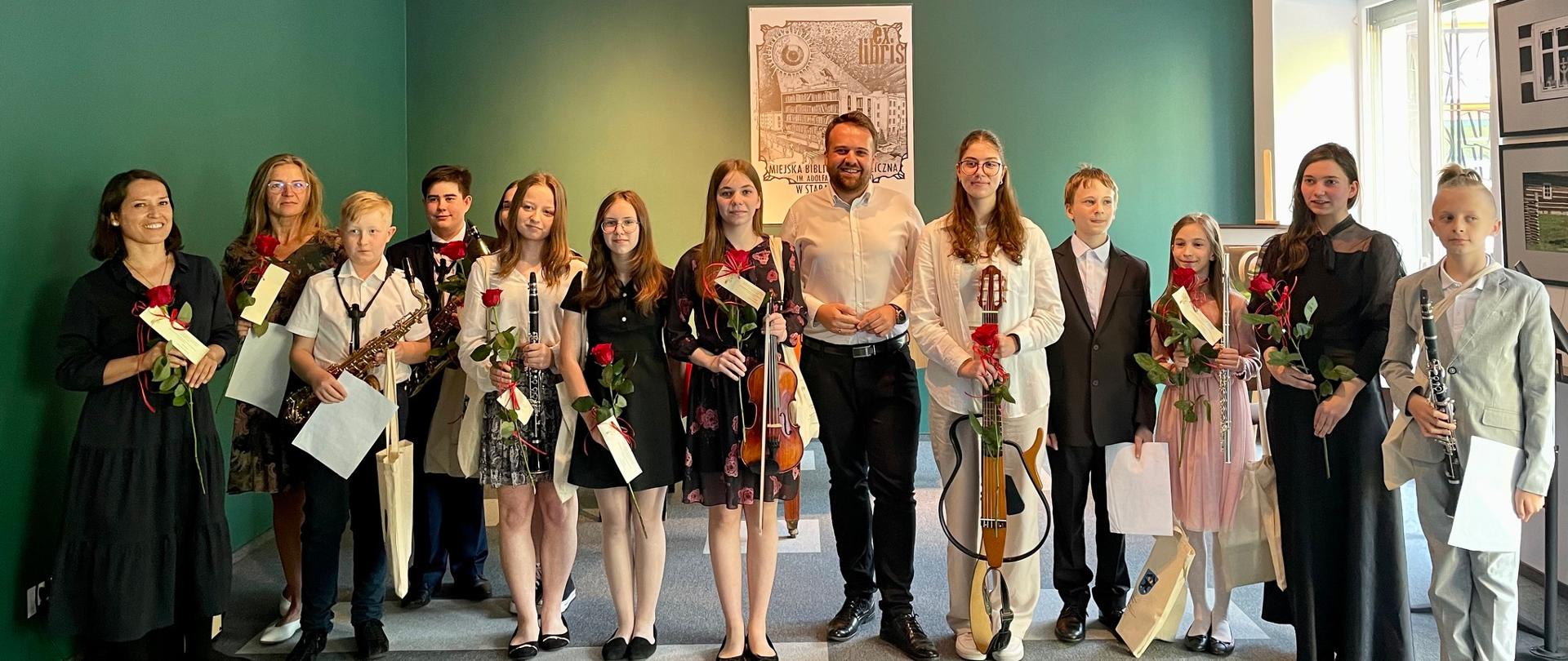 zdjęcie - uczniowie szkoły z prezydentem miasta i nauczycielem i panią dyrektor. Kobiety trzymają czerwone róże. foto Małgorzata Zatorska