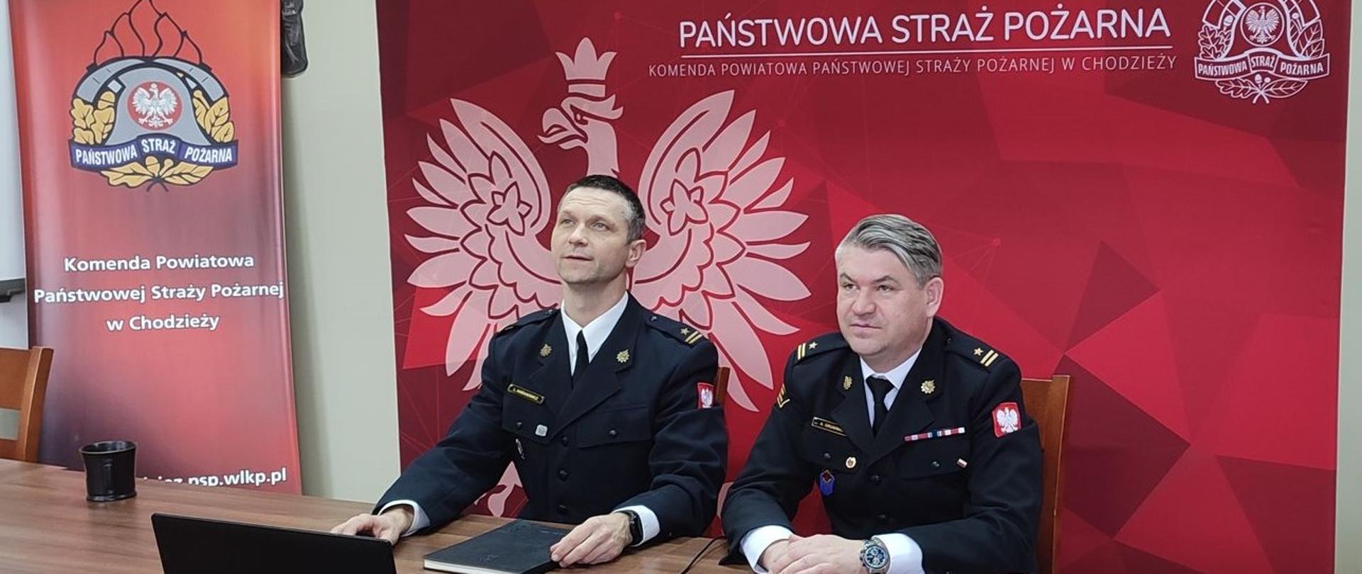 Zdjęcie przedstawia strażaków podsumowujących działalność Komendy za rok 2021.
W tle baner Komendy Powiatowej Państwowej Straży Pożarnej w Chodzieży.
