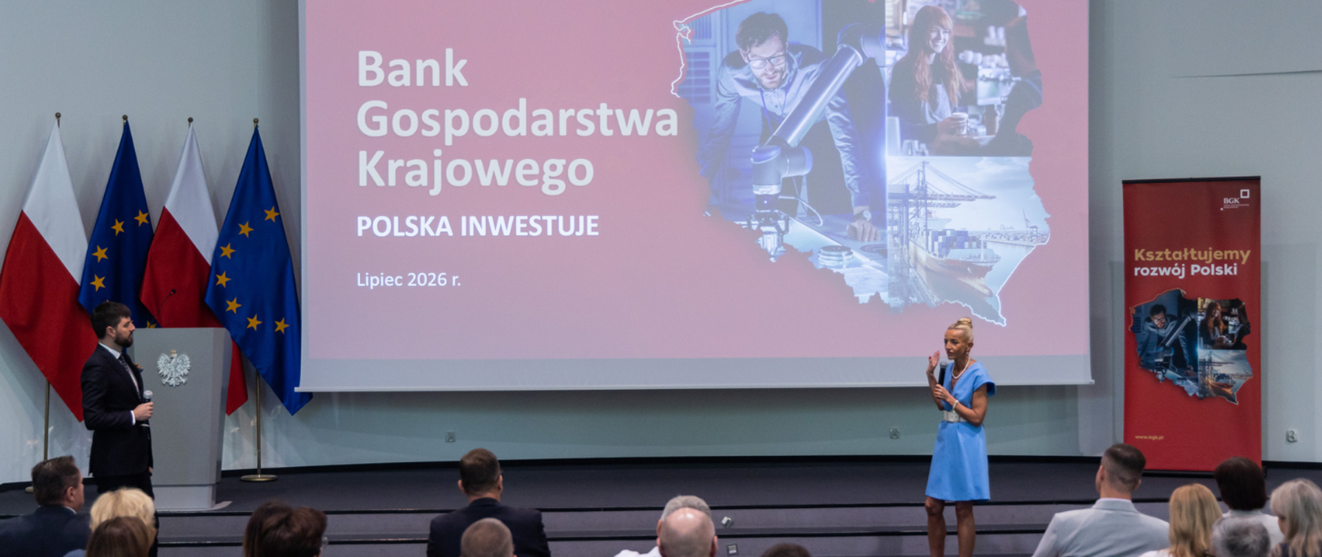 Prowadzący stoją przed wyświetlaną prezentacją i mówią do uczestników warsztatów. 