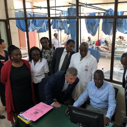 grupa kilku osób siedzi przy stole i patrzy w ekran komputera