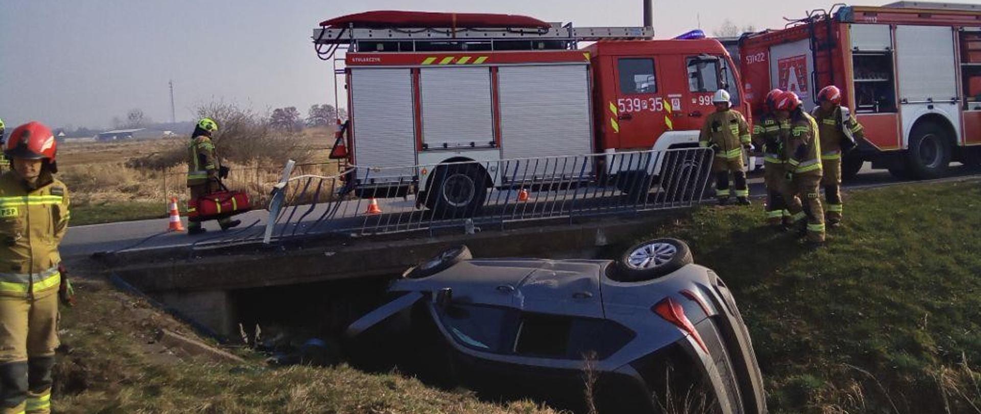 Auto w rowie, w tle pojazdy strażackie