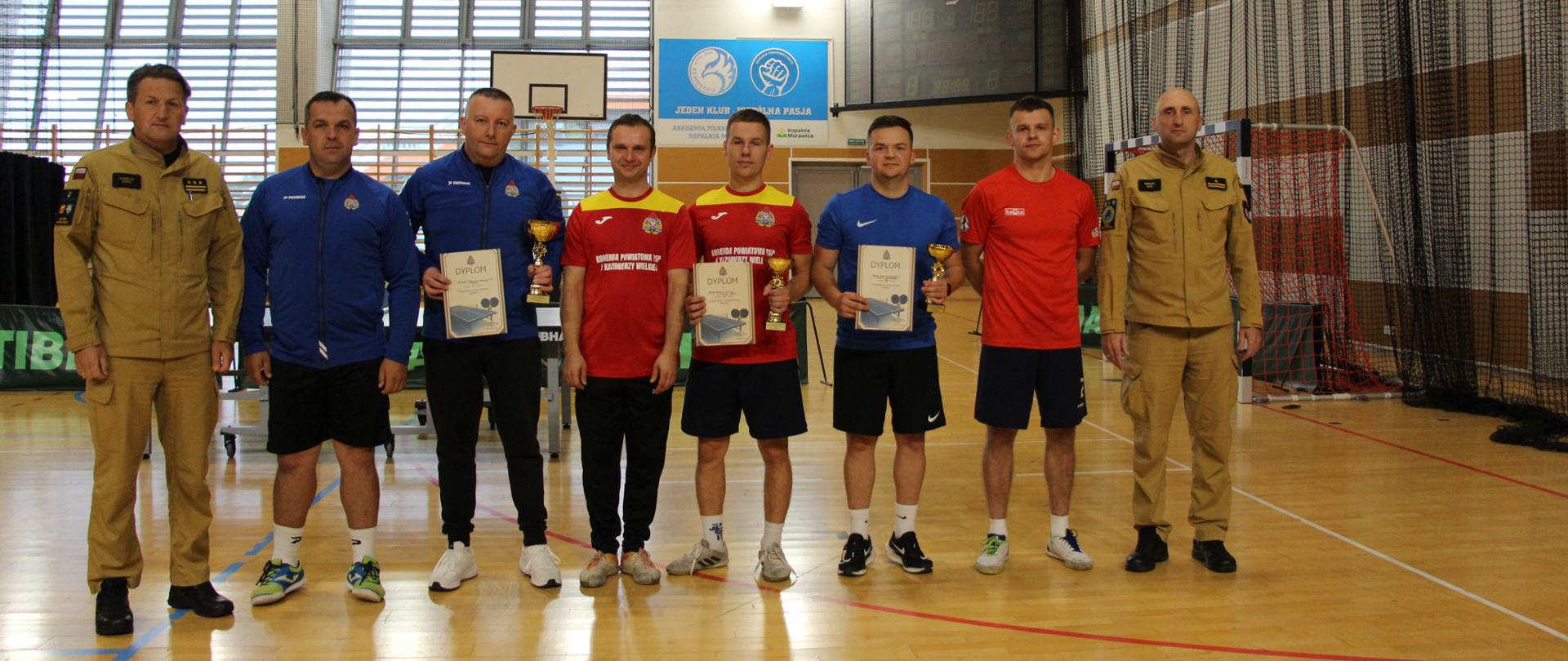 Na zdjęciu ustawieni w rzędzie zawodnicy turnieju w towarzystwie Komendanta Miejskiego PSP w Kielcach st. bryg. Mariusza Góry i dowódcy JRG Nr 3mł. bryg. Marka Dyka.