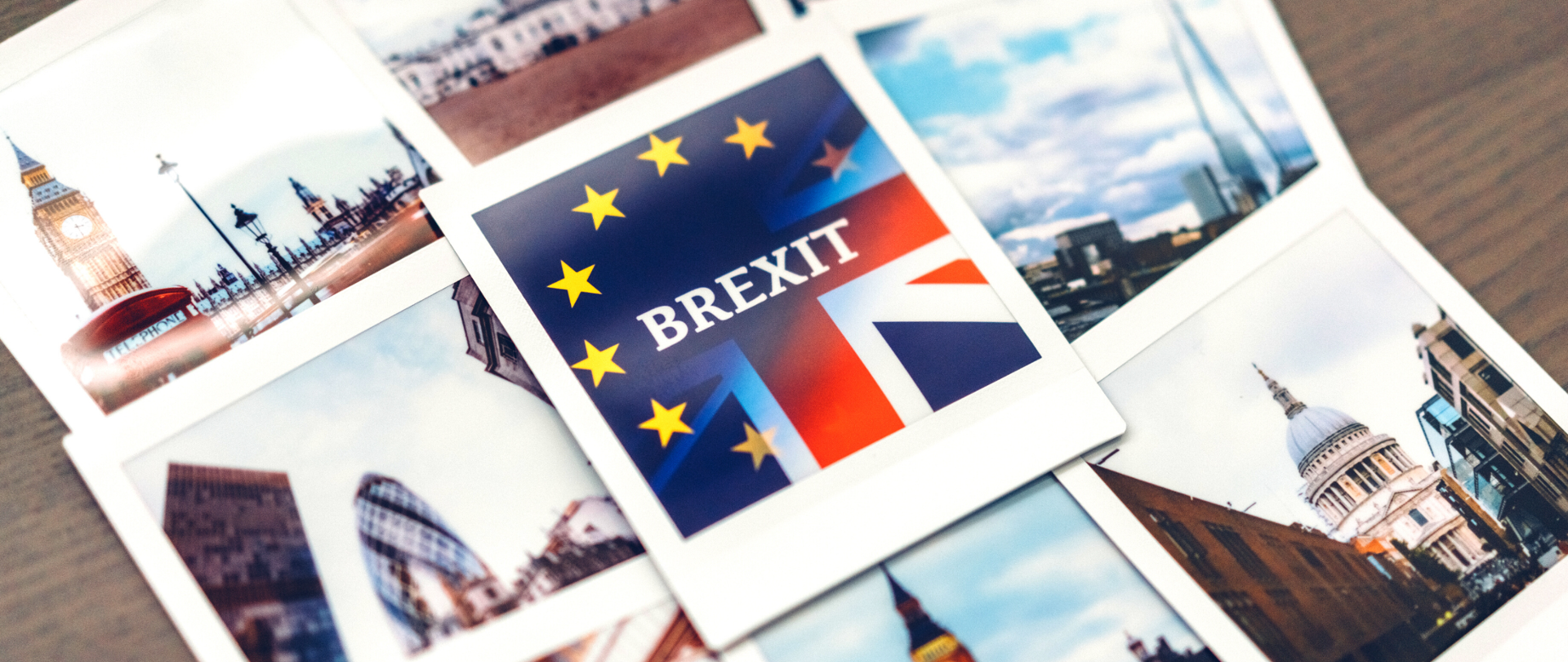 Leżące na stole wywołane zdjęcia typu polaroid. Na każdy - obrazki z Londynu. Na pierwszym planie leżące na samej górze zdjęcie z nachodzącymi na siebie flagami Unii Europejskiej i Wielkiej Brytanii oraz napisem Brexit.
