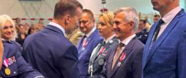 mężczyzna w garniturze, wicewojewoda, podaje rękę oficjelowi w garniturze, który został odznaczony 