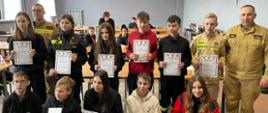 Uczestnicy Powiatowych Eliminacji Ogólnopolskiego Turnieju Wiedzy Pożarniczej trzymają dyplomy z prawej strony stoi p.o. Zastępca Komendanta Powiatowego PSP w Grodzisku Mazowieckim bryg. Marek Szymanek.