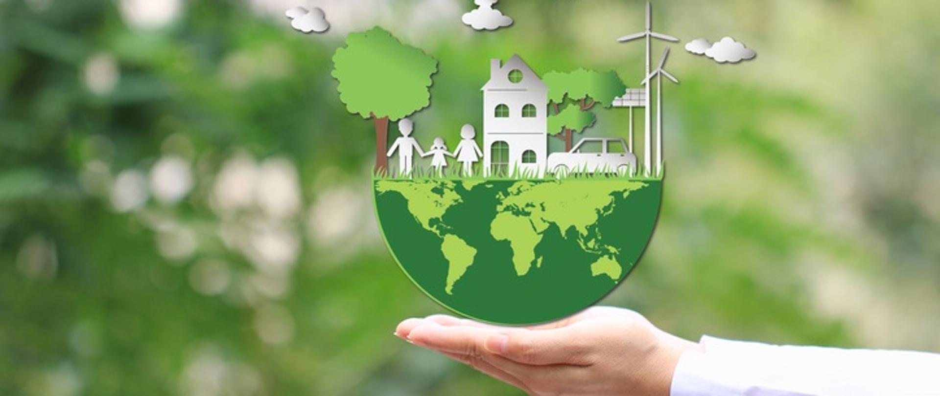 Ręka trzyma połówkę zielonego globu ziemskiego. Druga połowa globusa to białe postacie rodziny, domu na naturalnym zielonym tle. 