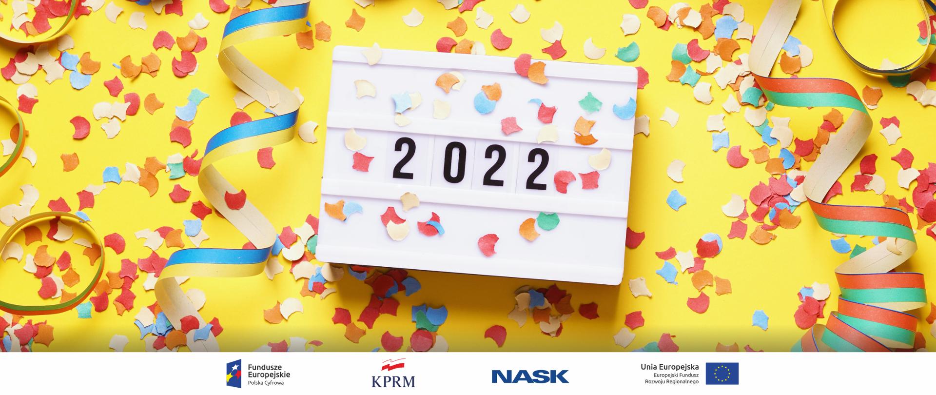 Grafika z żółtym tłem. Na niej serpentyna i confetti. Po środku kartka z kalendarza - 2022.