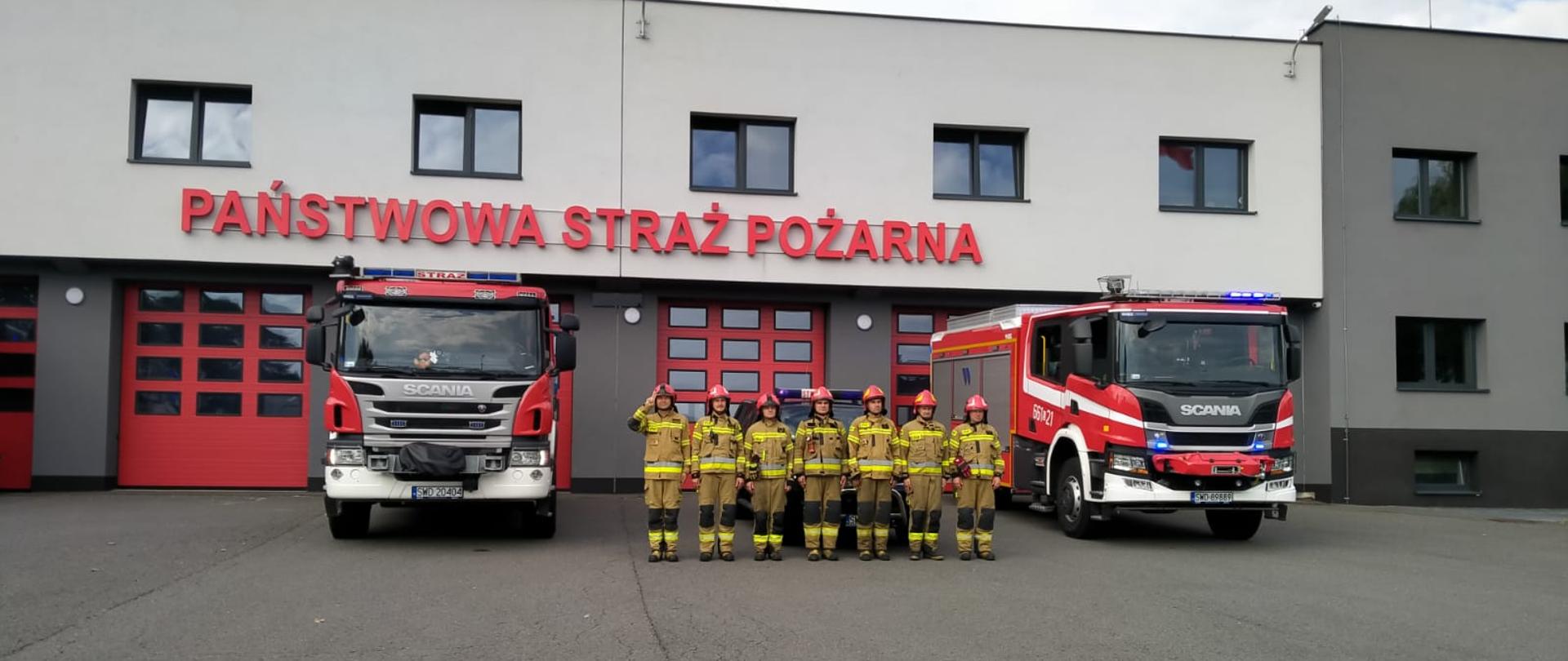 Na zdjęciu strażacy oddają hołd z okazji rocznicy Powstania Warszawskiego. W tle samochody pożarnicze oraz budynek JRG.