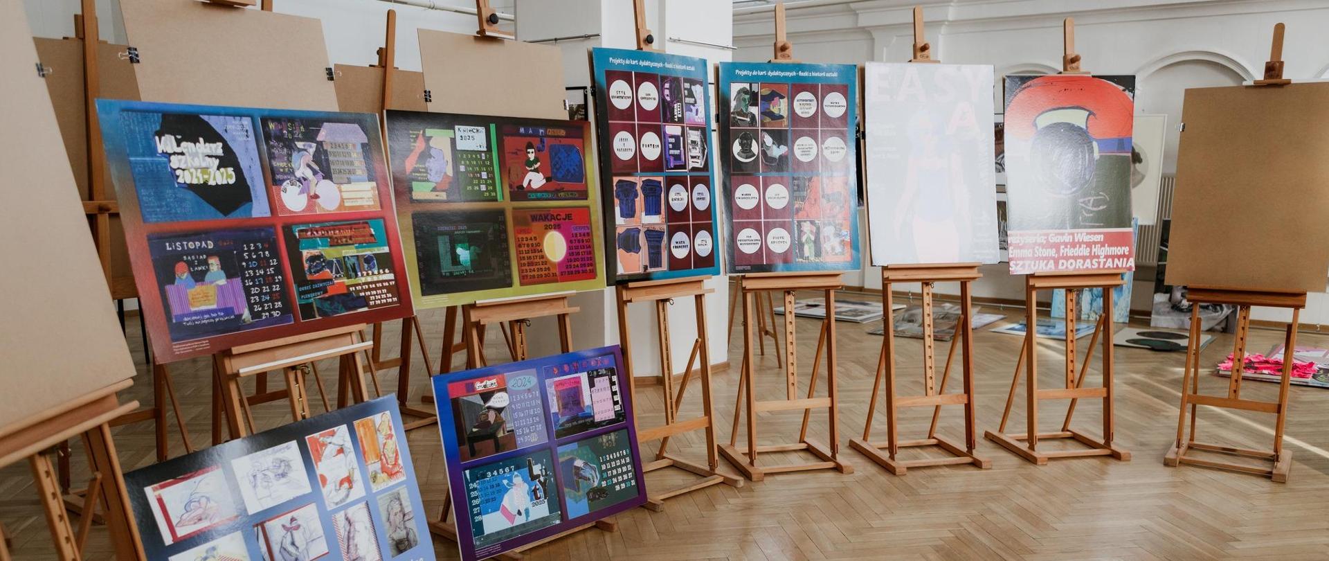 Zdjęcie przedstawia salę wystawową w której na sztalugach umieszczono prace uczniów klas piątych.