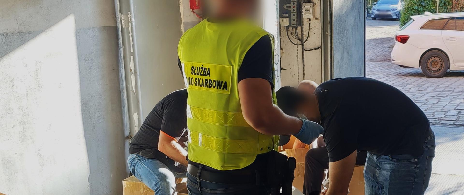 Funkcjonariusze Służby Celno-Skarbowej sprawdzają kartony z towarem.