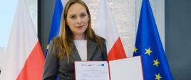 Minister funduszy i polityki regionalnej Katarzyna Pełczyńska-Nałęcz trzyma w dłoniach podpisaną z BGK umowę na wsparcie zielonej transformacji miast
