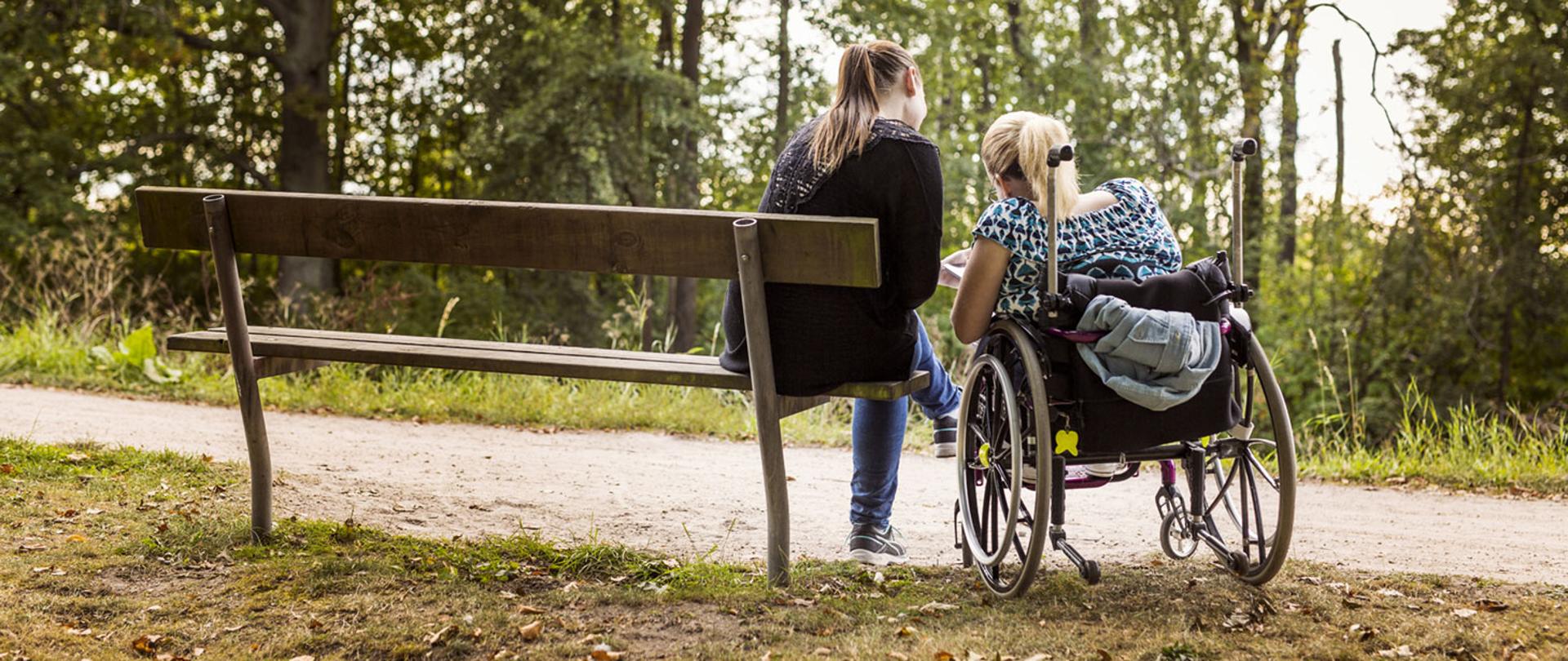 Niepełnosprawna kobieta na wózku z asystentką