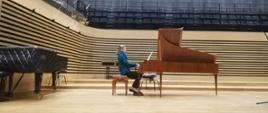 Kobieta gra na brązowym fortepianie historycznym na scenie sali koncertowej PSM w Jastrzębiu-Zdroju