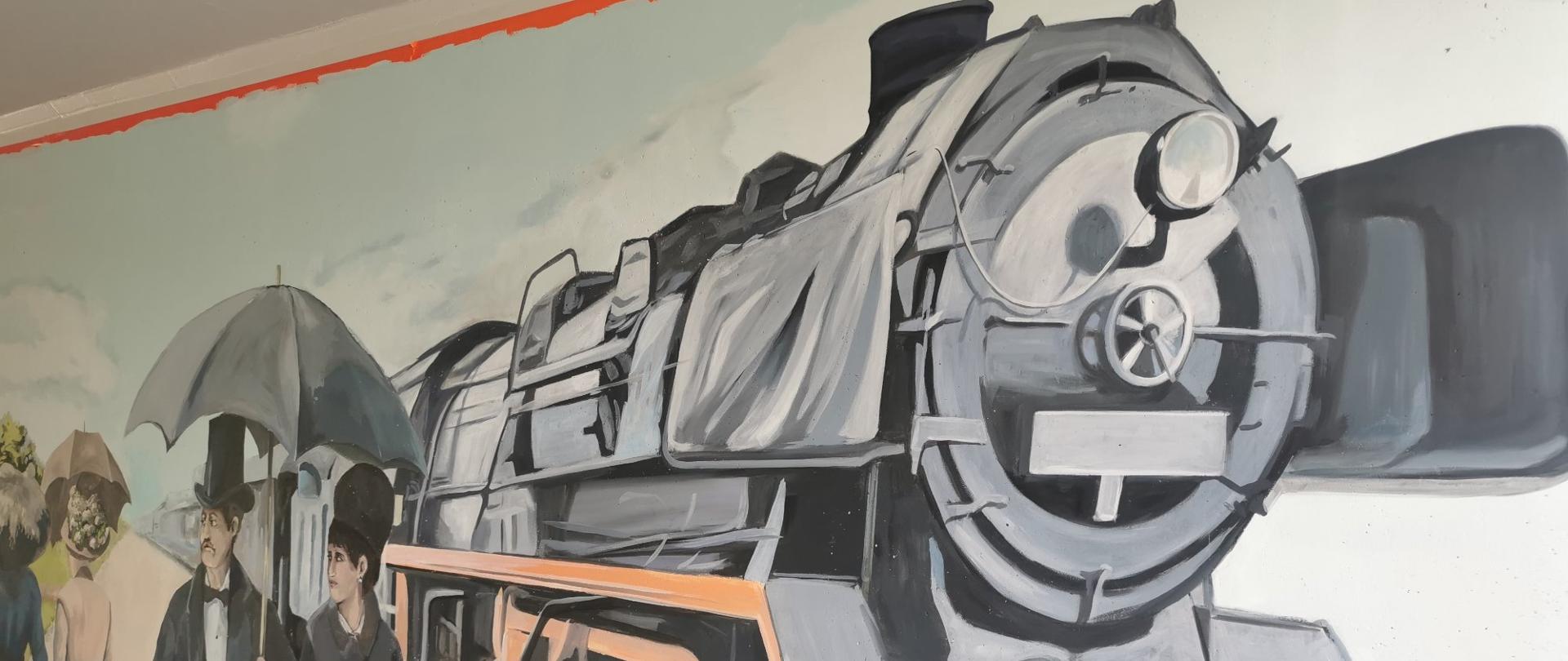 Mural przedstawiający starą lokomotywę, obok niej mężczyzna i kobieta idą pod parasolką