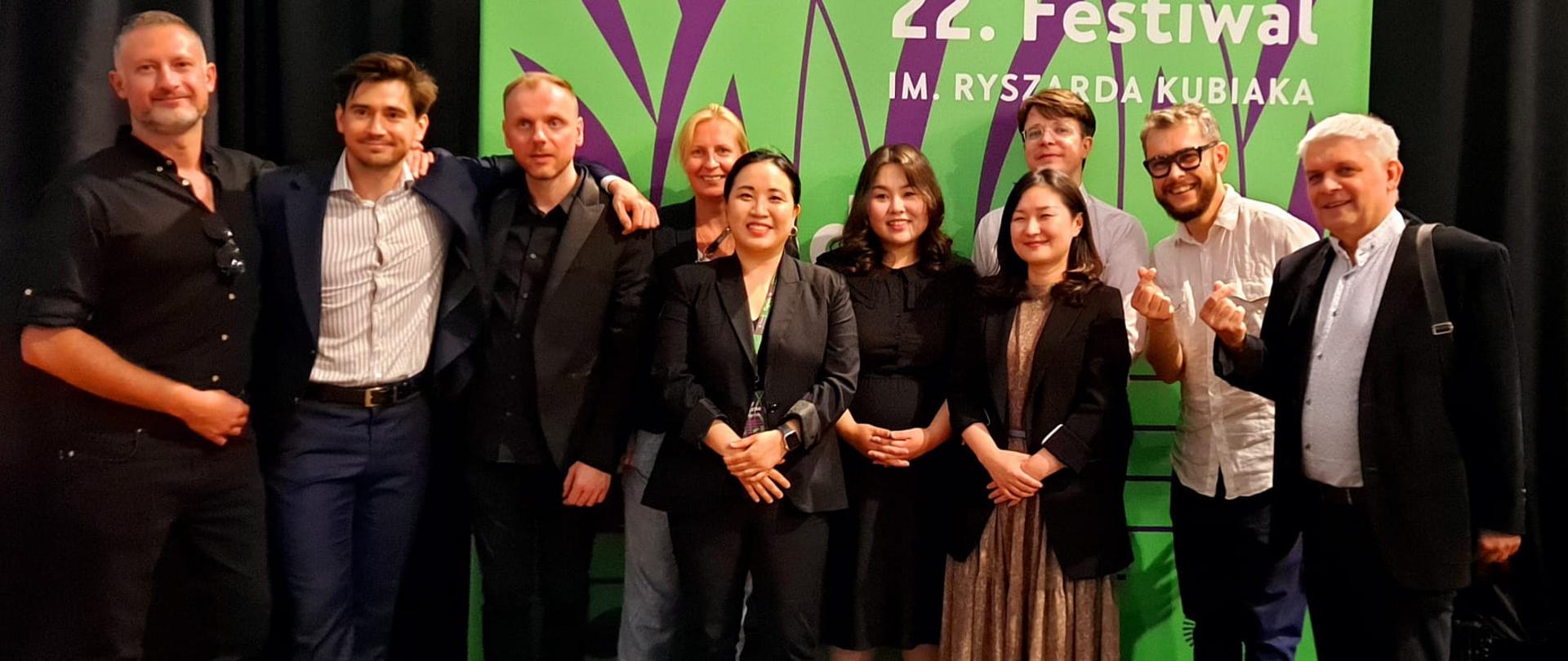 Wykonawcy koncertu z organizatorami i autorami tekstu na tle baneru festiwalu Music Gardens Festival