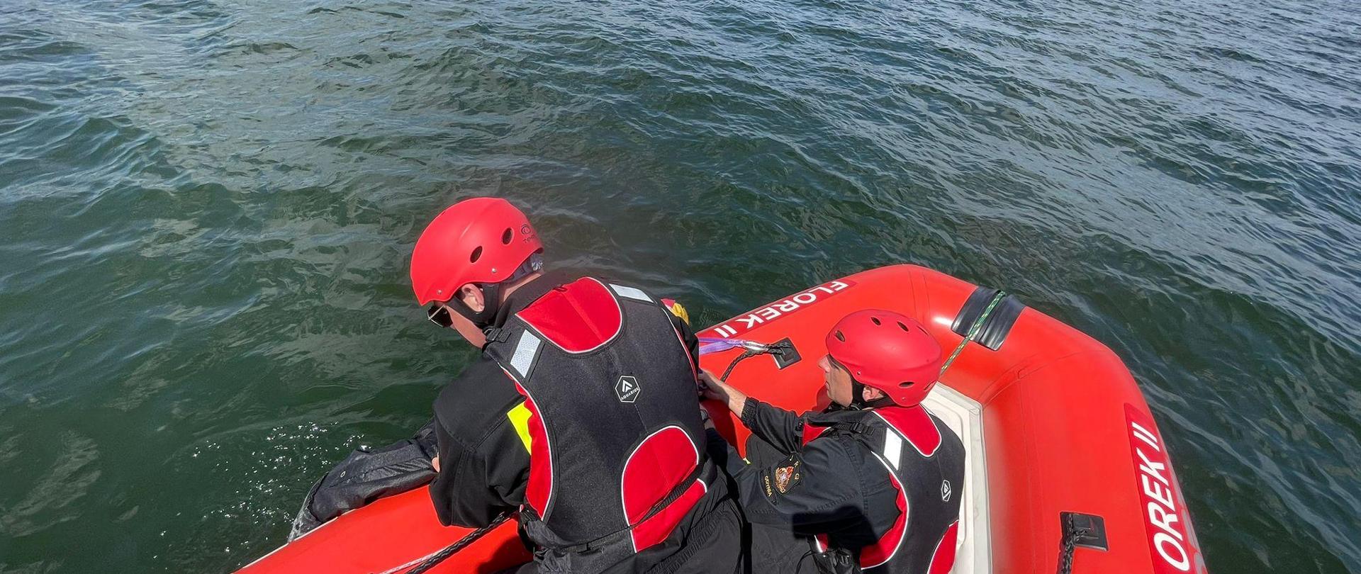 Strażacy na łodzi. Wyciągają manekina z wody