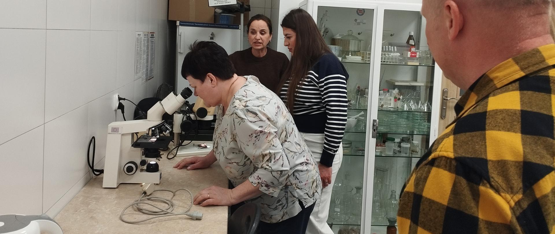 kobieta pochylona nad binokularem ogląda preparat