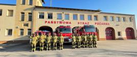 Strażacy stojąc na baczność na tle samochodów gaśniczych oddają cześć poległym strażakom z Ukrainy.