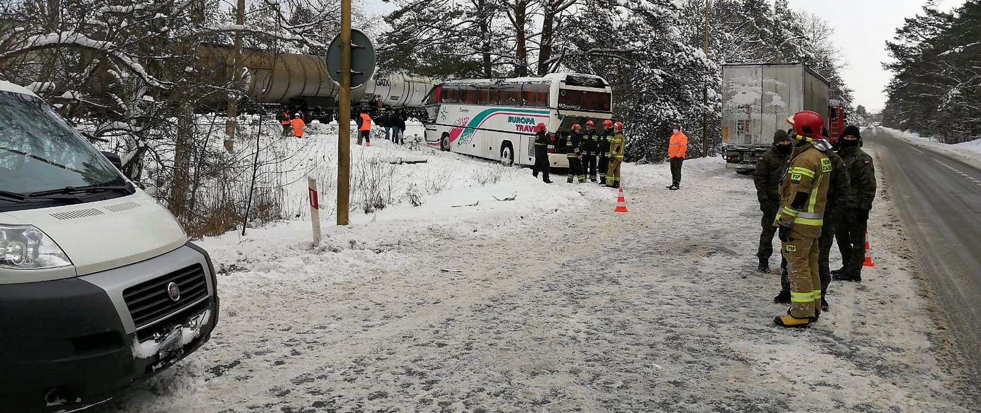 Miejsce akcji: pas pomiędzy torem kolejowym i drogą krajową nr 3, gdzie stoi bus, autobus, TIR, i samochód pożarniczy. Na torze stoi pociąg towarowy z cysternami. 6 strażaków w mundurach bojowych, pracownicy kolei, 3 żołnierzy.