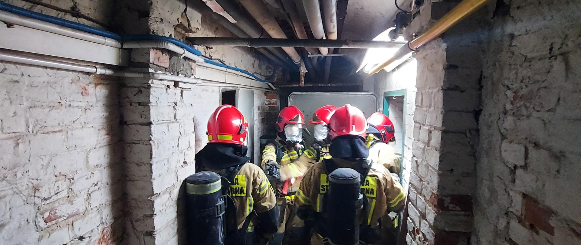 Strażacy w trakcie ćwiczenia, sprawdzają możliwości poruszania się i poszukiwania w pomieszczeniach.
