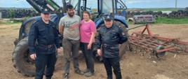 Na zdjęciu funkcjonariusze oraz kobieta i mężczyzna. Za nimi stoi sprzęt rolniczy.