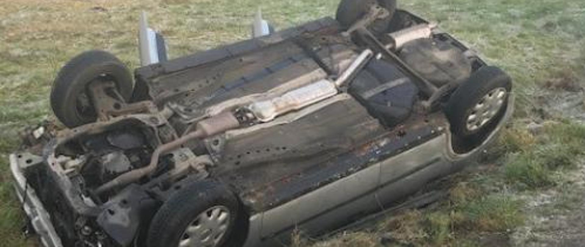 na zdjęciu samochód osobowy na dachu poza drogą