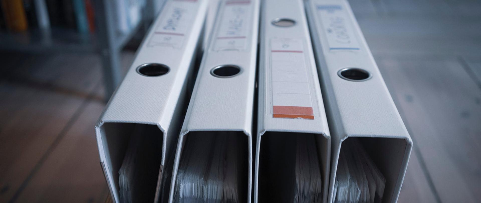 Cztery segregatory z dokumentami obok siebie.