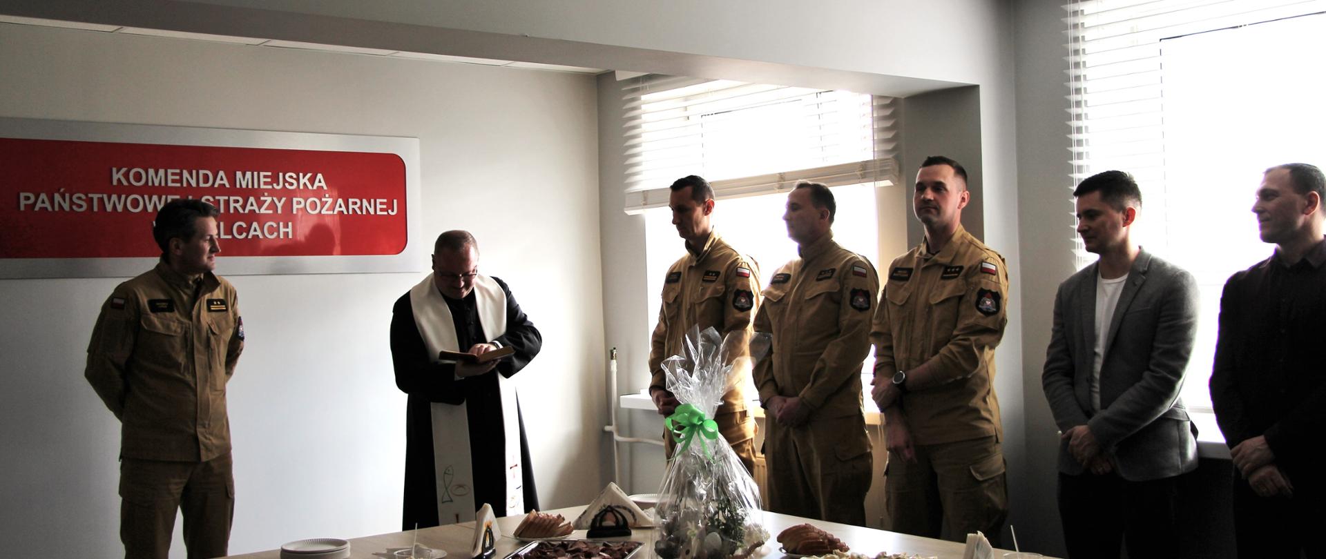 Zdjęcie przedstawia uczestników spotkania wielkanocnego pochylonych w trakcie modlitwy prowadzonej przez kapelana.