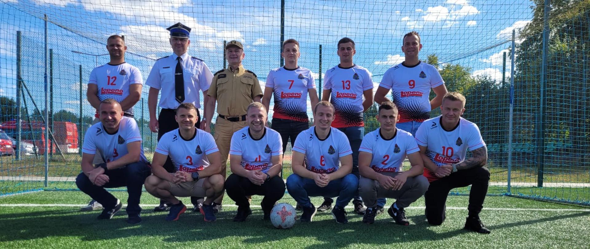 drużyna strażaków KP PSP Kozienice pozująca do zdjęcia na boisku na tle bramki