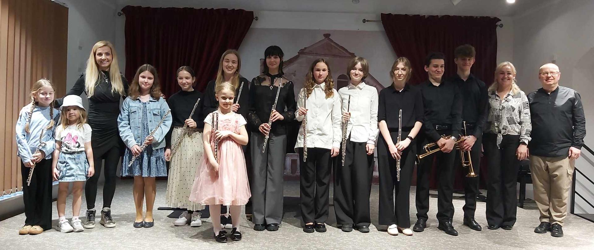 Na scenie wykonawcy audycji klasy fletu, trąbki i puzonu razem z nauczycielami i akompaniatorami
