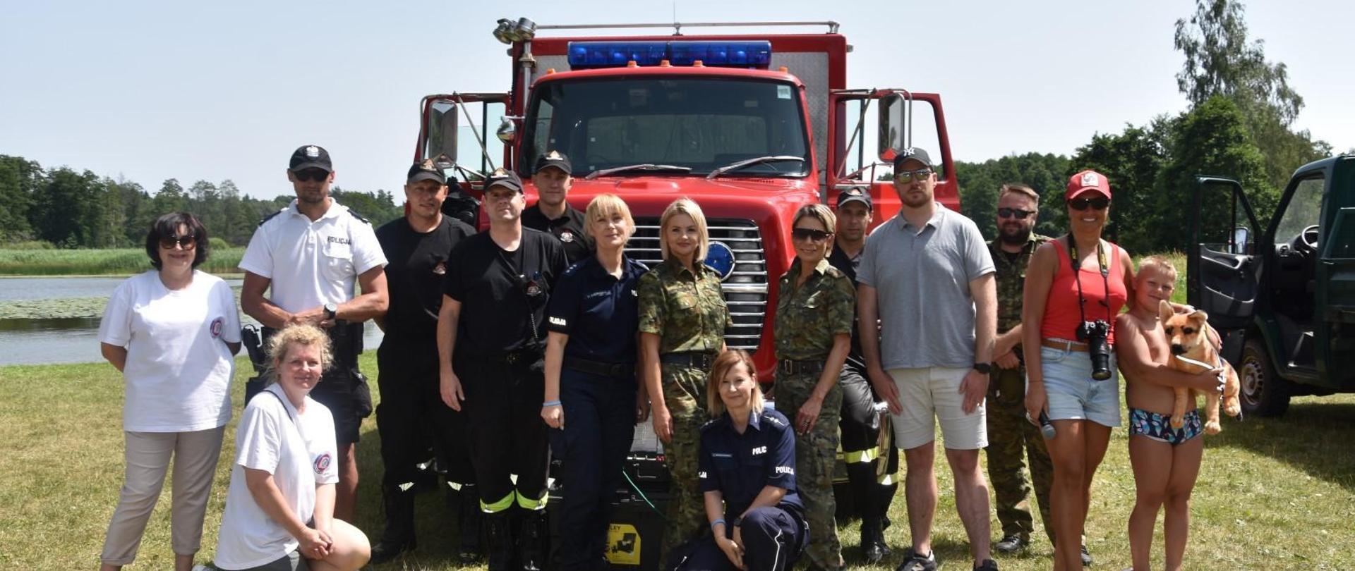 Funkcjonariusze i uczestnicy pokazów stoją przed samochodem SGRWN