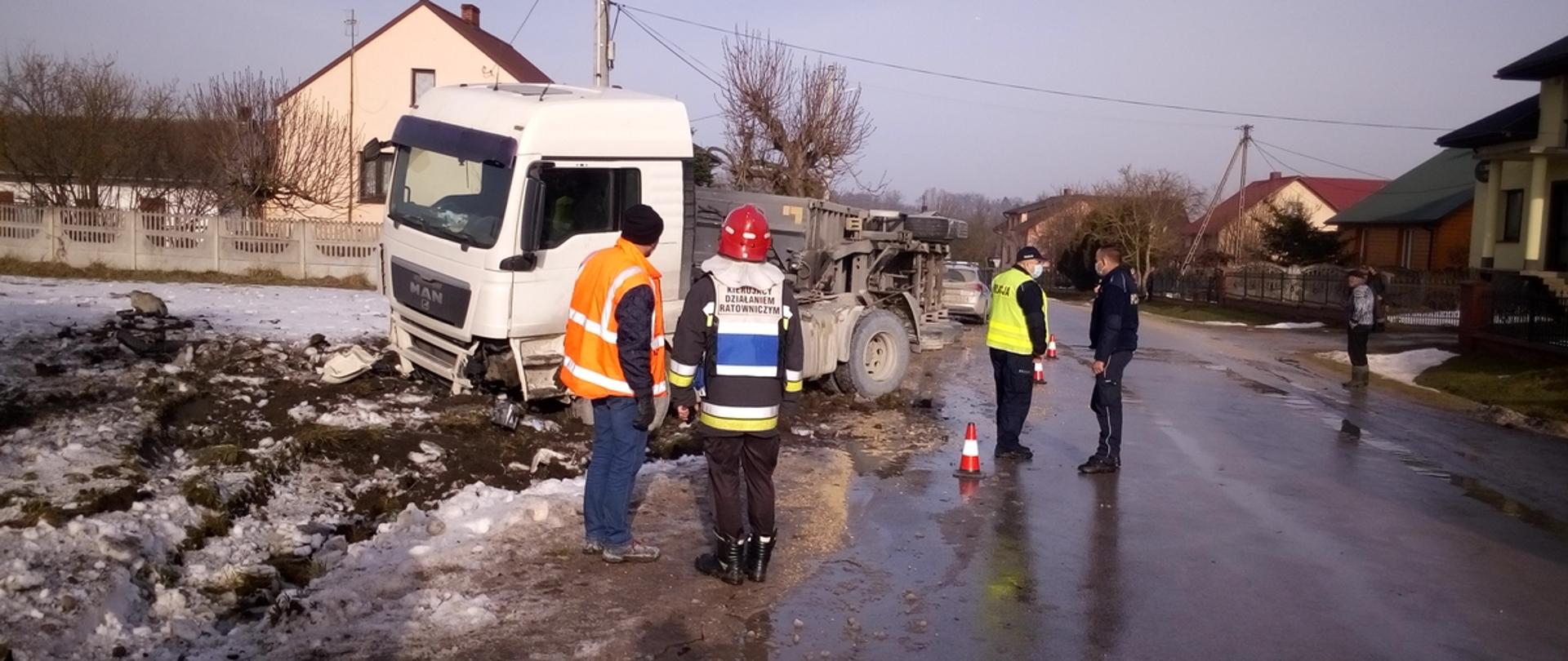 Zdjęcie przedstawia przewróconą na bok naczepę ciężarówki, z której wysypało się 25 ton kruszywa.
