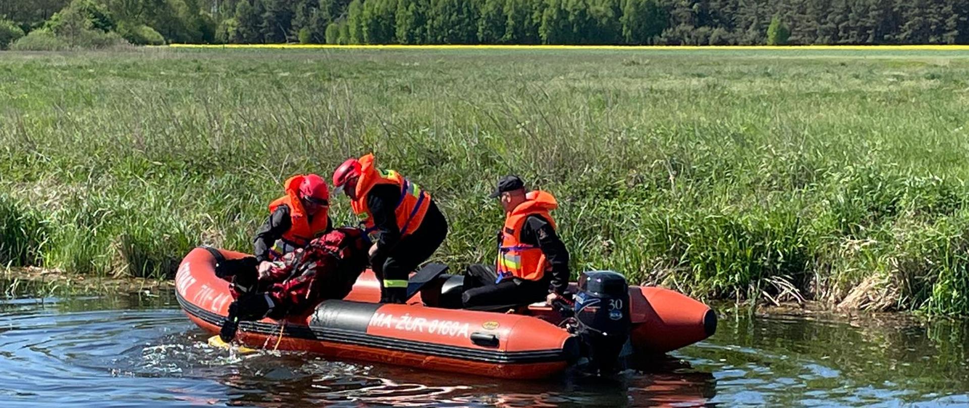 Ćwiczenia w ramach doskonalenia zawodowego na rzece. Trzech strażaków wykonuje ćwiczenia na pontonie.