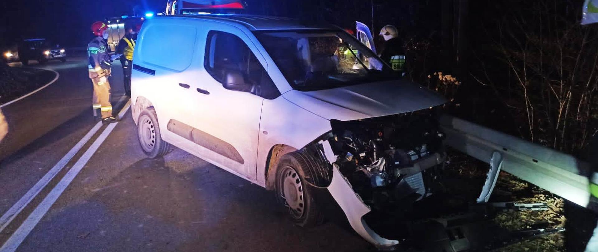 Na zdjęciu widać zbliżenie od przodu samochodu, który uderzył w barierkę oraz strażaków. 