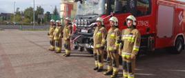 Zdjęcie przedstawia druhów Ochotniczej Straży Pożarnej stojących przy nowym samochodzie ratowniczo - gaśniczym
