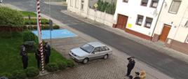 Dzień flagi RP. Poczet flagowy dokonuje podnoszenia flagi państwowej na masz. Dowódca pocztu i asystujący salutują. Poczet wystepuje w umundurowaniu wyjściowym. Na przeciwko masztu w ubraniach koszarowych oraz służbowych stoja strażacy z dwóch zmian służbowych JRG.