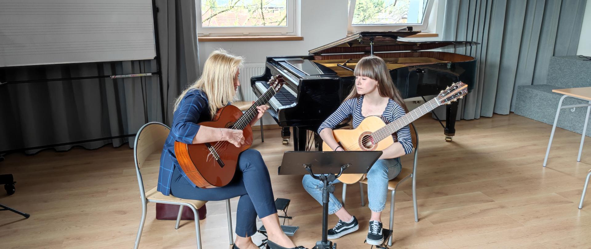 Sylwetki dwóch gitarzystek podczas warsztatów w sali kameralnej ZSM w Krośnie