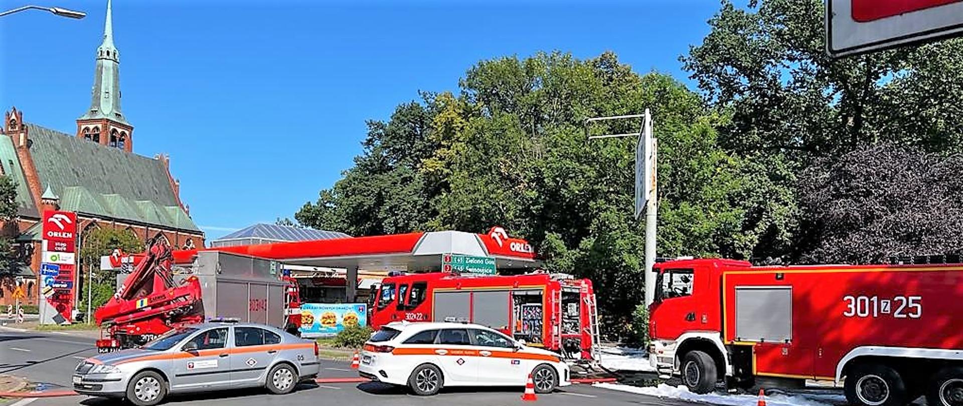 Ruch na ulicy Kopernika zablokowany przez 3 pojazdy pożarnicze oraz 2 samochody nadzoru ruchu. Na drugim planie widać stacje paliw oraz kościół.