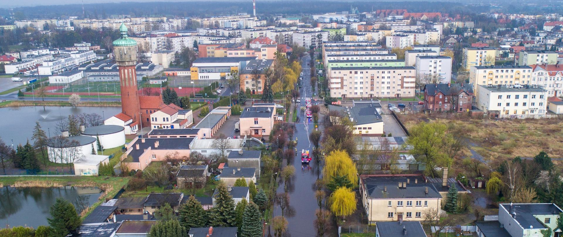 Zdjęcie z lotu ptaka, przedstawia panoramę Wrześni , zalaną ulicę i trzy wozy strażackie wypompowujące wodę