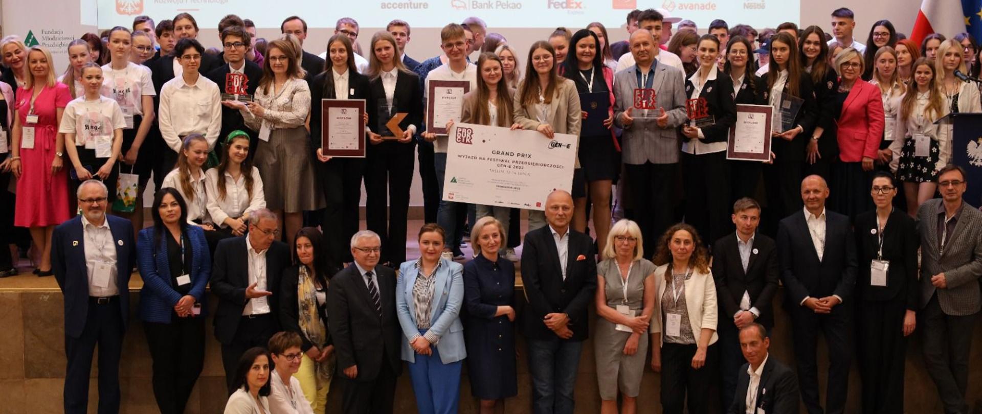 Minister Olga Semeniuk podczas finału Produkcik 2022. Na zdjęciu widać wszystkich uczestników konkursu i panią minister.