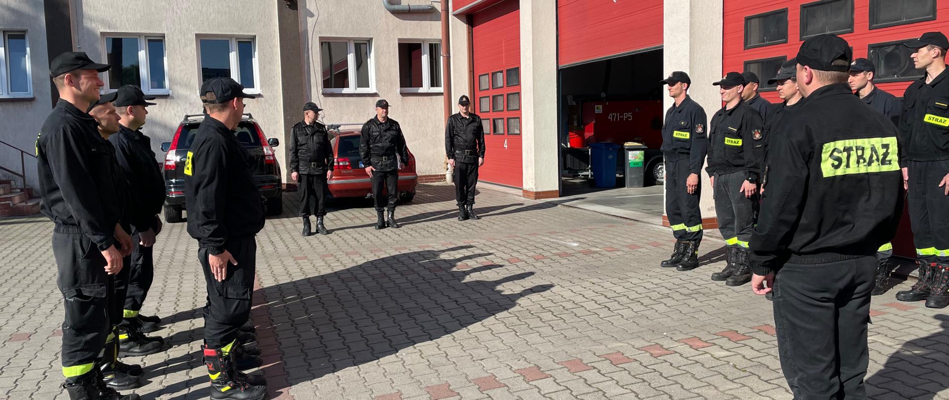 Zdjęcie przedstawia zmianę służbową podczas której komendant powiatowy PSP w Kole wręcza wyróżnionemu strażakowi nagrodę pieniężną Wielkopolskiego Komendanta Wojewódzkiego PSP