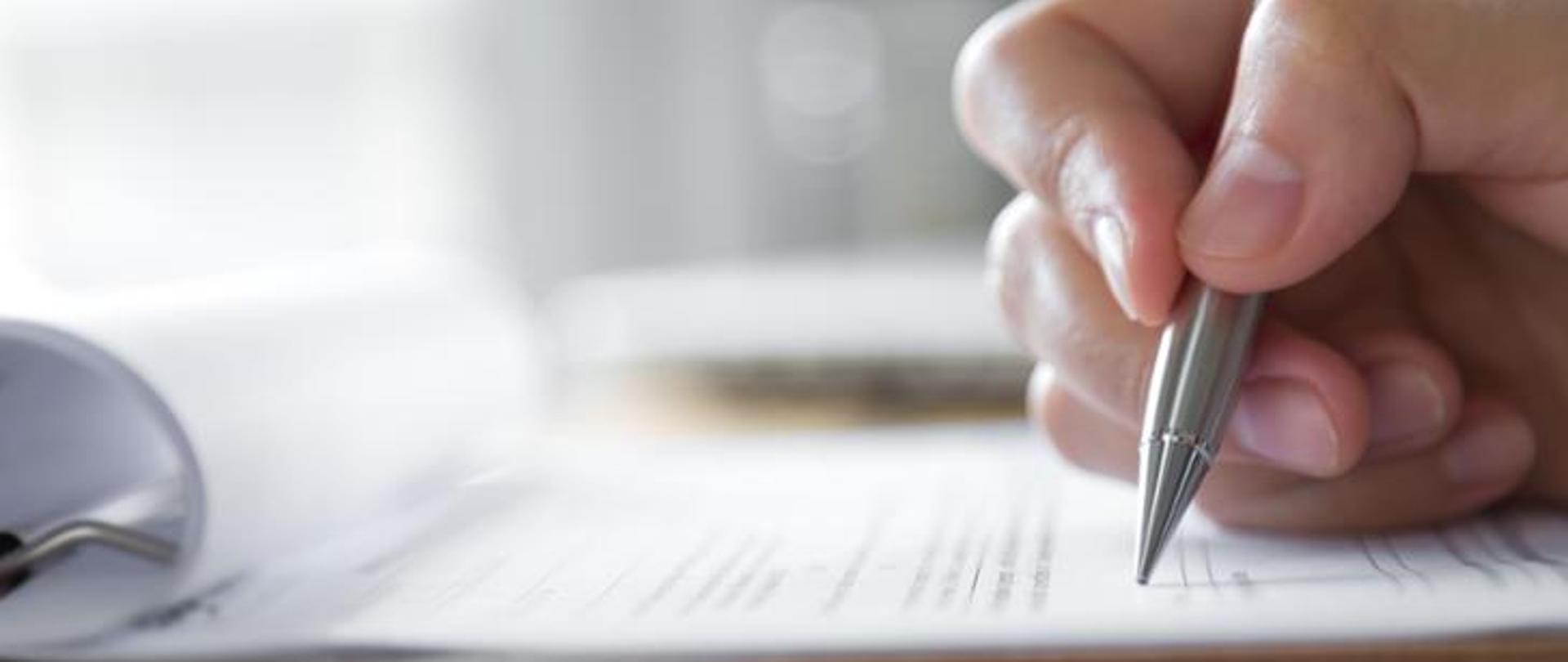 dłoń trzymająca pióro