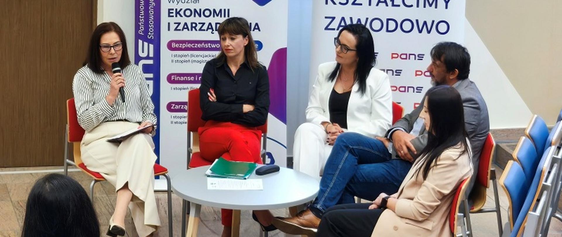 Pięć osób siedzi przy stoliku na scenie