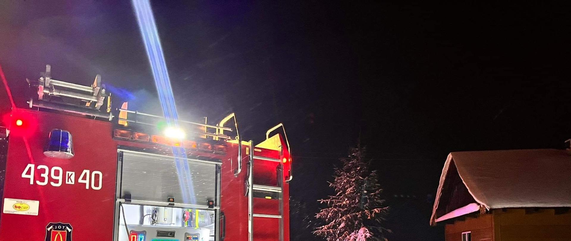 Na zdjęciu widać samochód ratowniczo gaśniczy z rozwinięta linią główną do pożaru domu mieszkalnego.