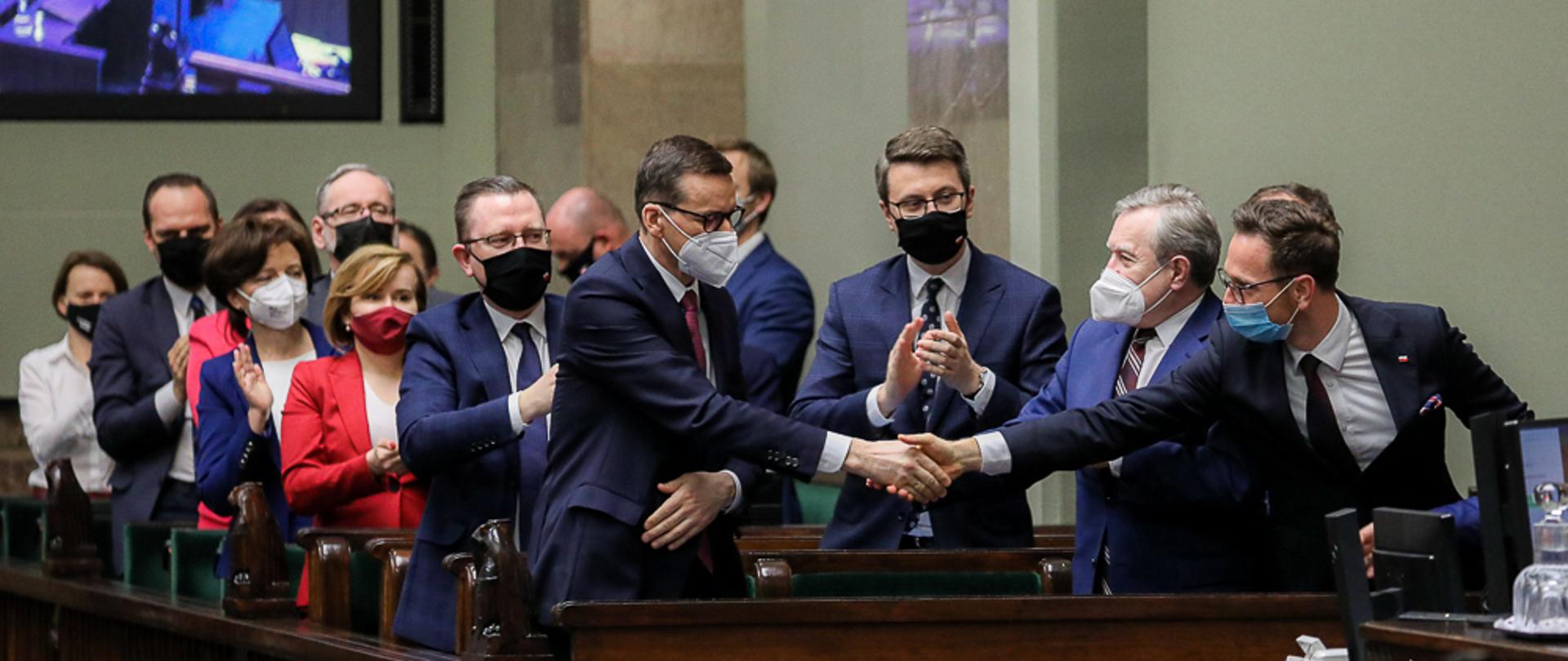 Premier Mateusz Morawiecki podaje w sejmie rękę ministrowi Budzie.